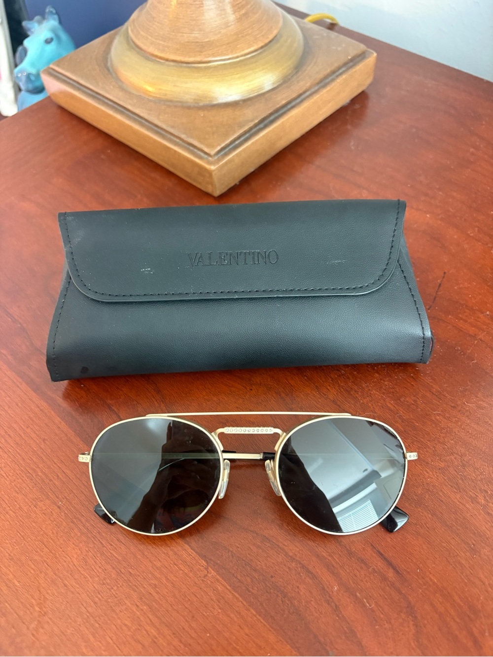 Valentino round gold sunglasses with black lens and case.